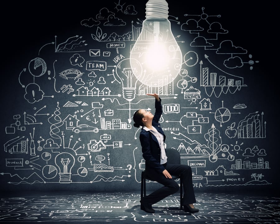 young-businesswoman-sitting-on-chair-with-big-light-bulb-above